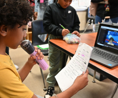 Student with microphone and laptop engaging in classroom arts